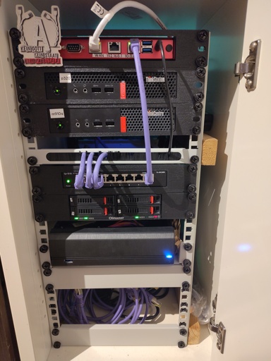 Photo of a small white wooden cabinet. It's open and contains many small computers, mounted in casings between two metal rails